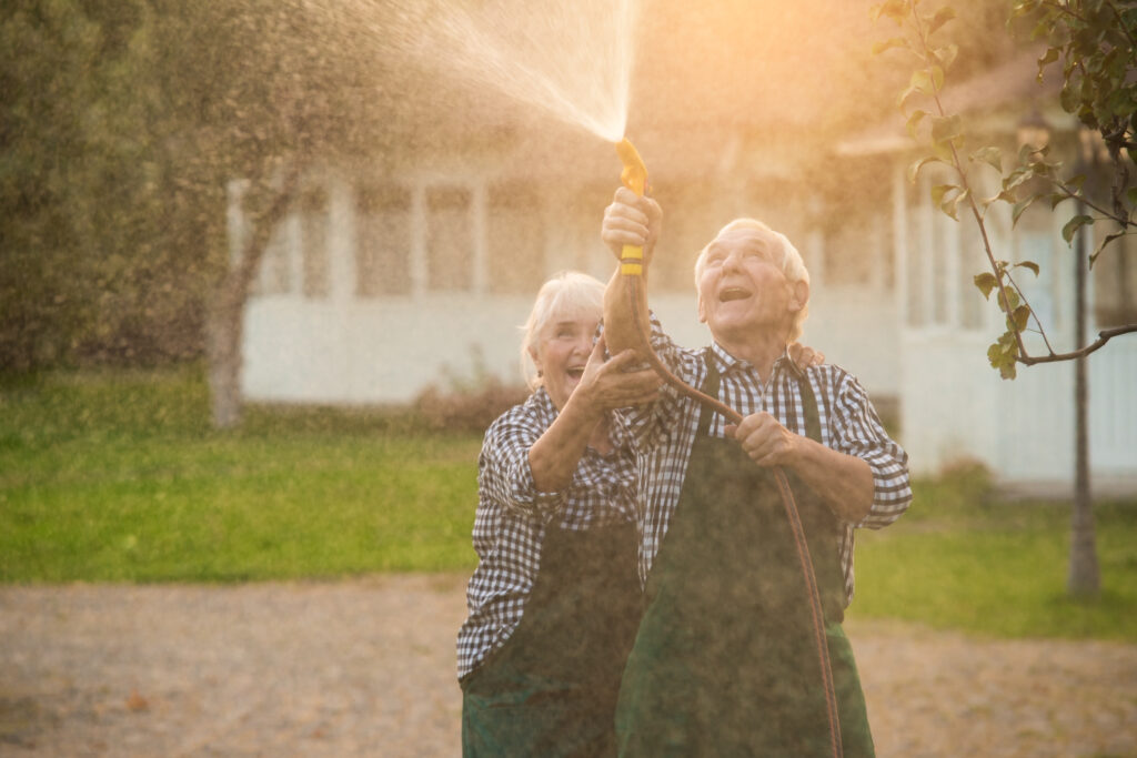 Elderly couple with garden hose. Old people having fun.