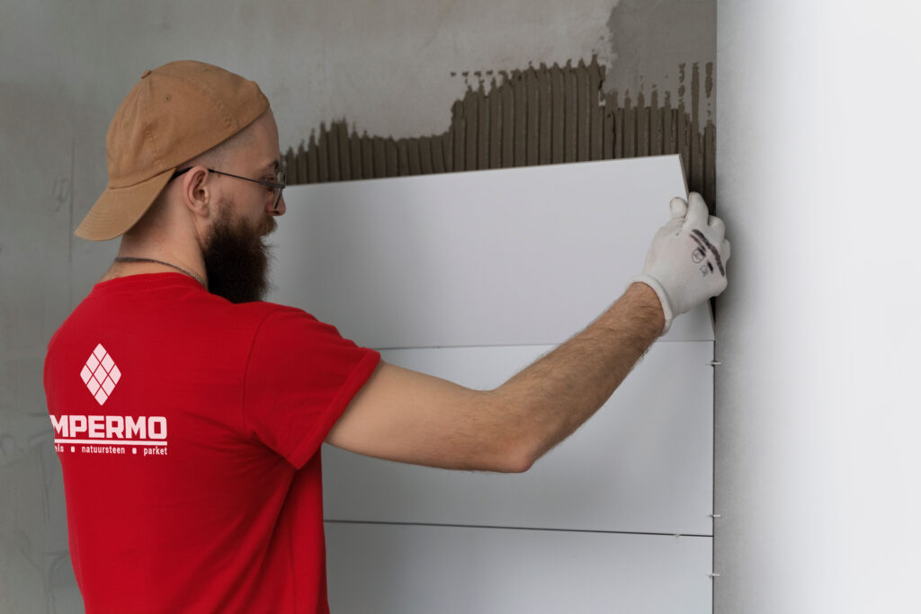 Impermo background of about section of worker putting new tiles on the wall.